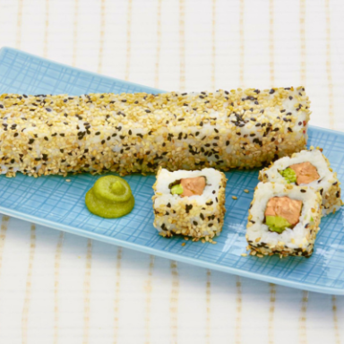 Eine Sushi-Rolle mit Sesam, dazu zwei Stücke Sushi und ein Klecks Wasabi.