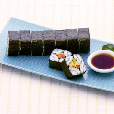 Bunte Sushi-Rollen auf einem blauen Teller mit Sojasauce.