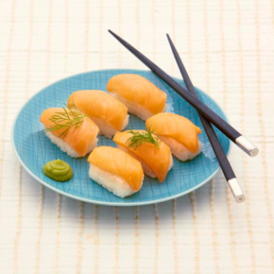 Sechs Sushi-Stücke mit Lachs auf einem blauen Teller, dazu Wasabi und Essstäbchen.