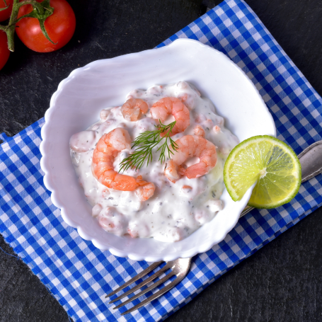 Feinkostsalat garniert mit Riesengarnelen und frischen Kräutern, serviert in einer Schüssel.